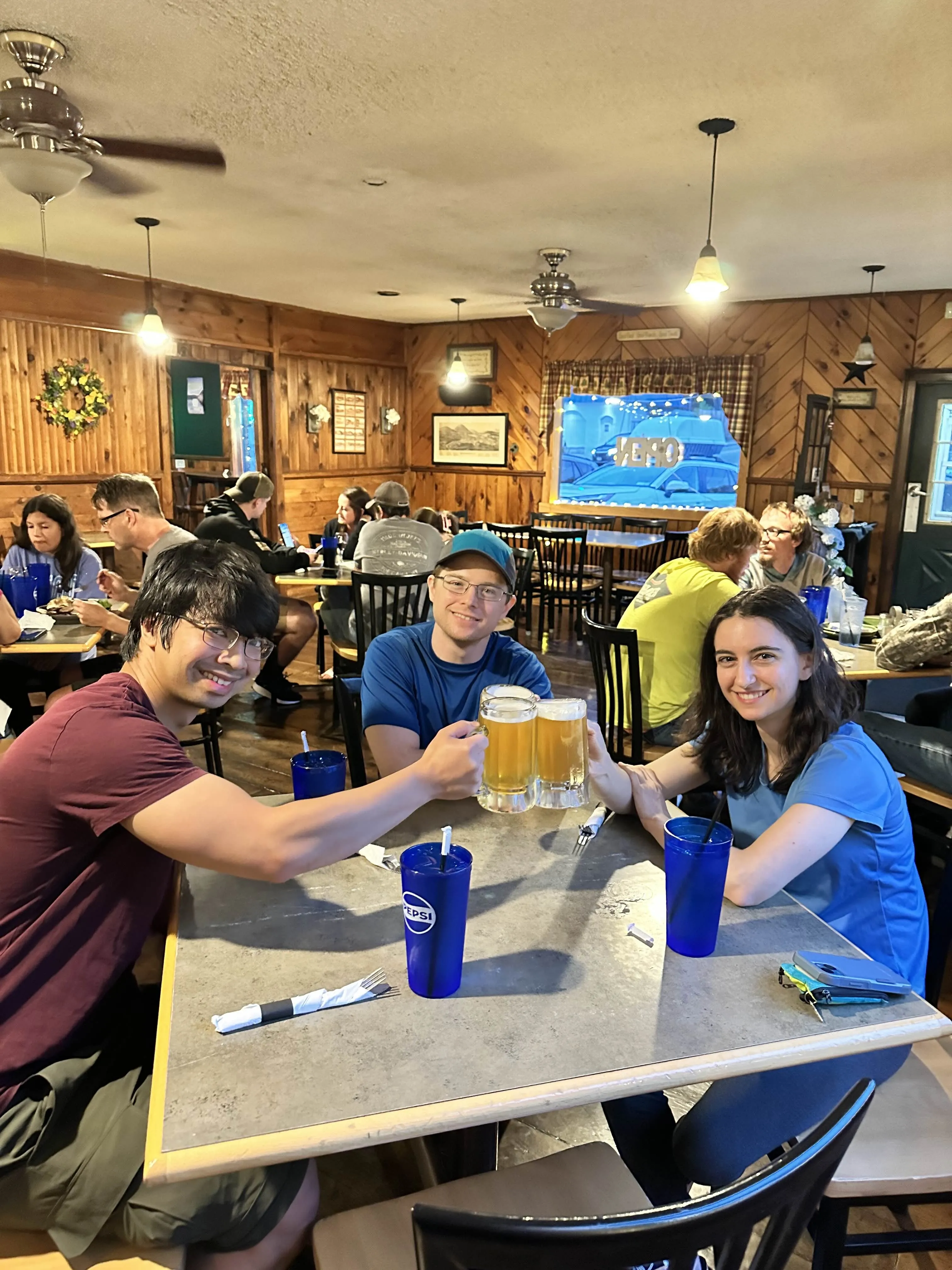 The three hikers at a restaurant, cheers'ing beer glasses